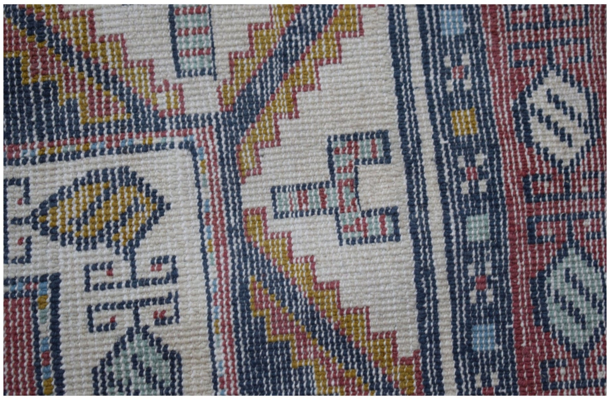 A close-up of a vintage handwoven Turkish rug featuring geometric patterns in red, blue, and gold.