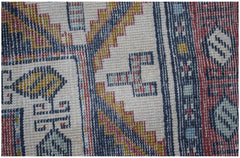 A close-up of a vintage handwoven Turkish rug featuring geometric patterns in red, blue, and gold.