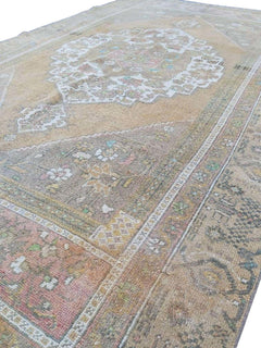 A vintage handmade Turkish wool rug featuring a faded medallion pattern in muted earth tones.
