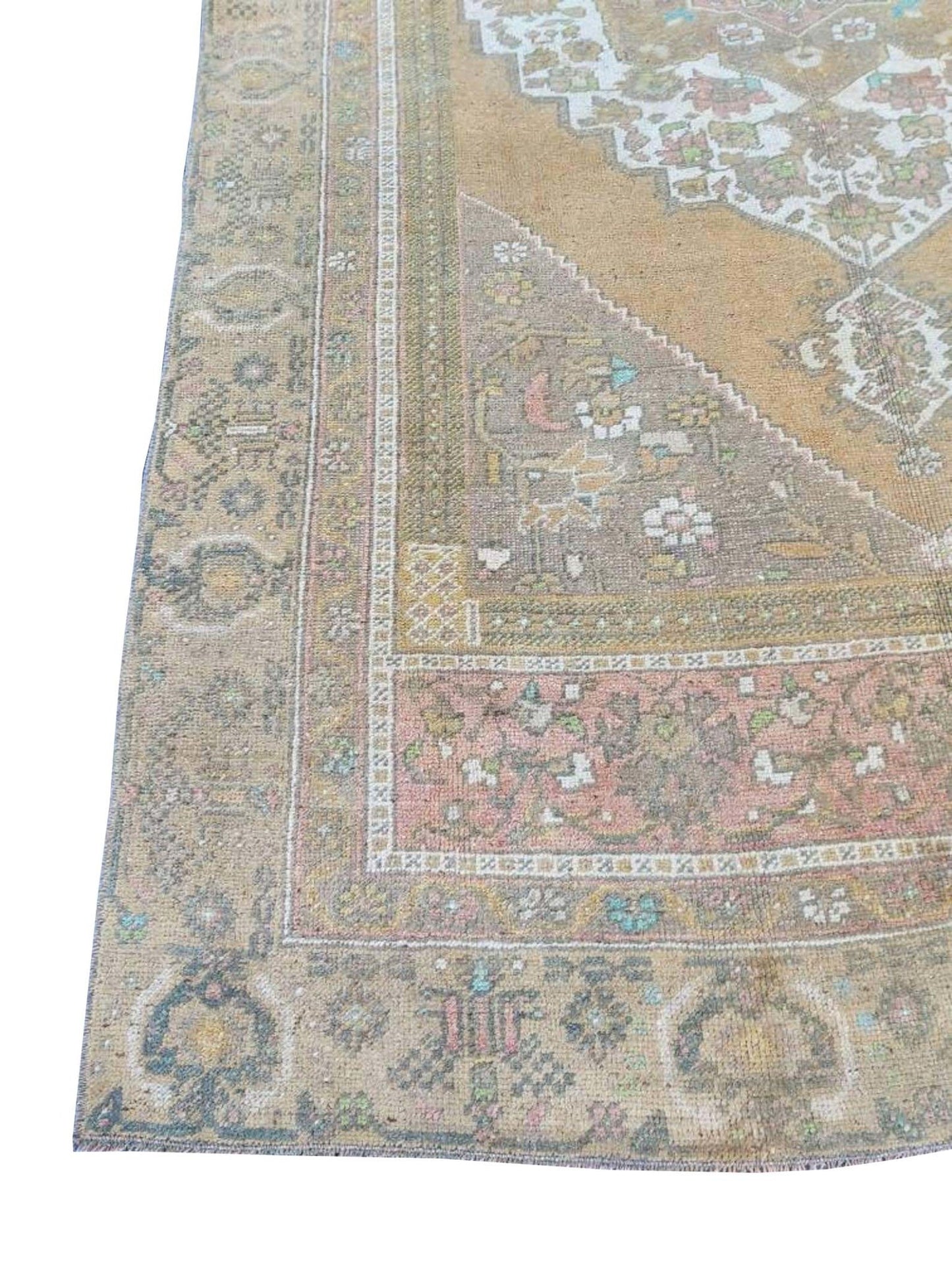 A vintage handmade Turkish wool rug featuring a faded geometric pattern in muted earth tones.