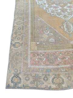 A vintage handmade Turkish wool rug featuring a faded geometric pattern in muted earth tones.