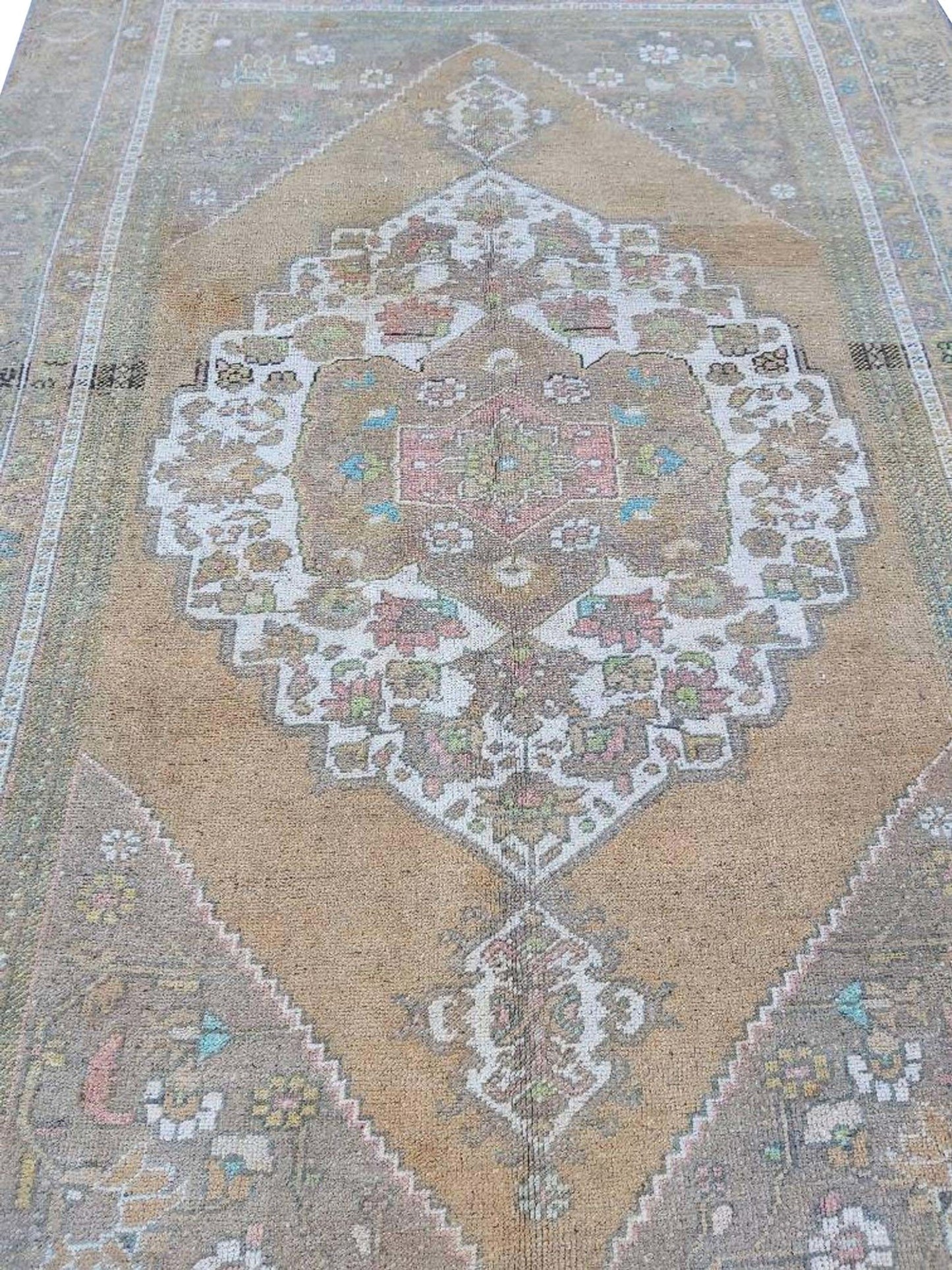 A vintage handmade Turkish wool rug featuring a central medallion in muted earth tones.