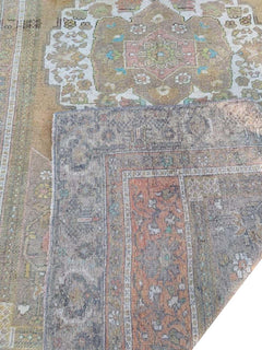 A vintage handmade Turkish wool rug featuring a faded geometric pattern in muted earth tones.