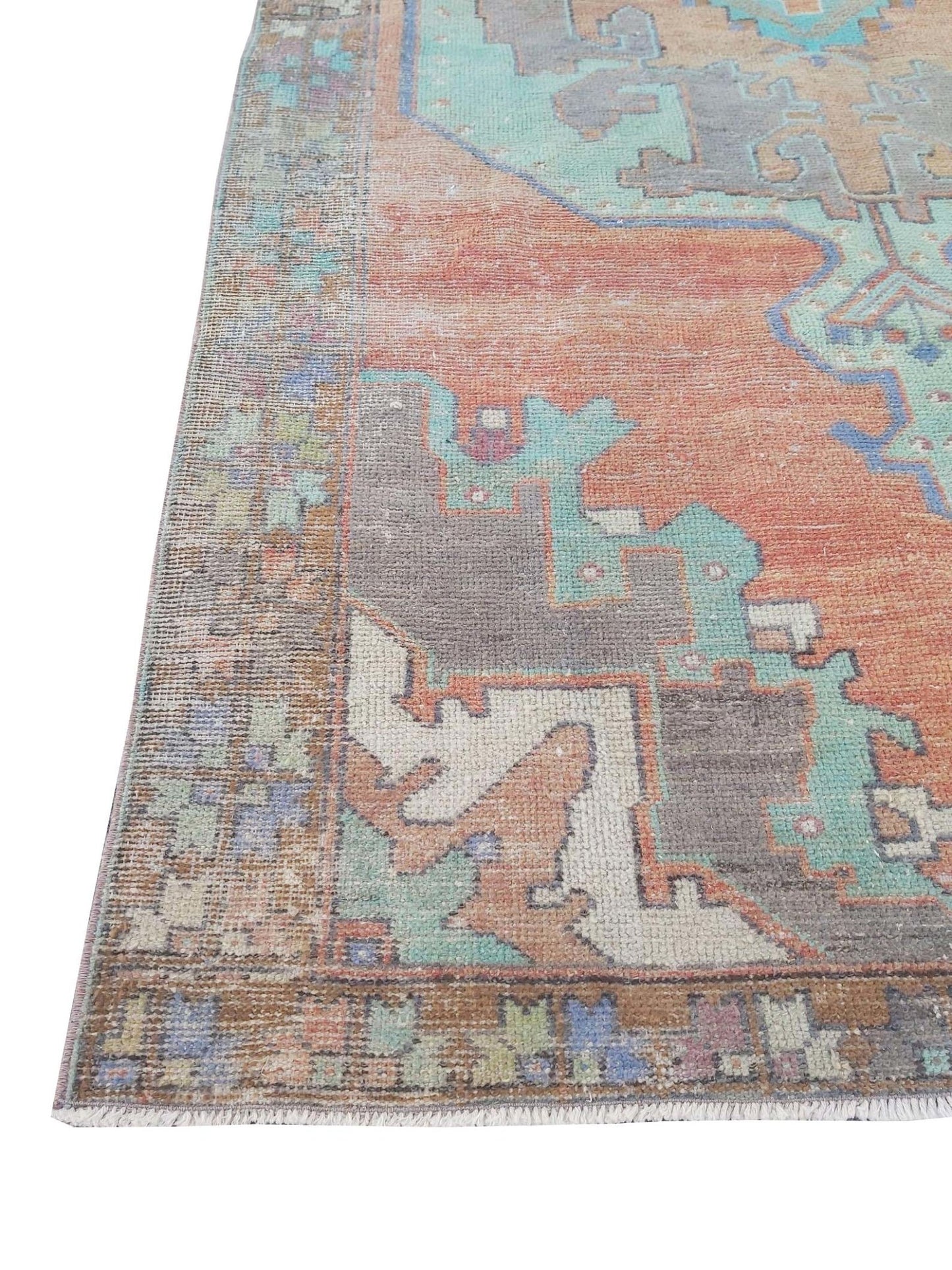 A vintage handmade Turkish rug featuring geometric patterns in orange, teal, and grey.