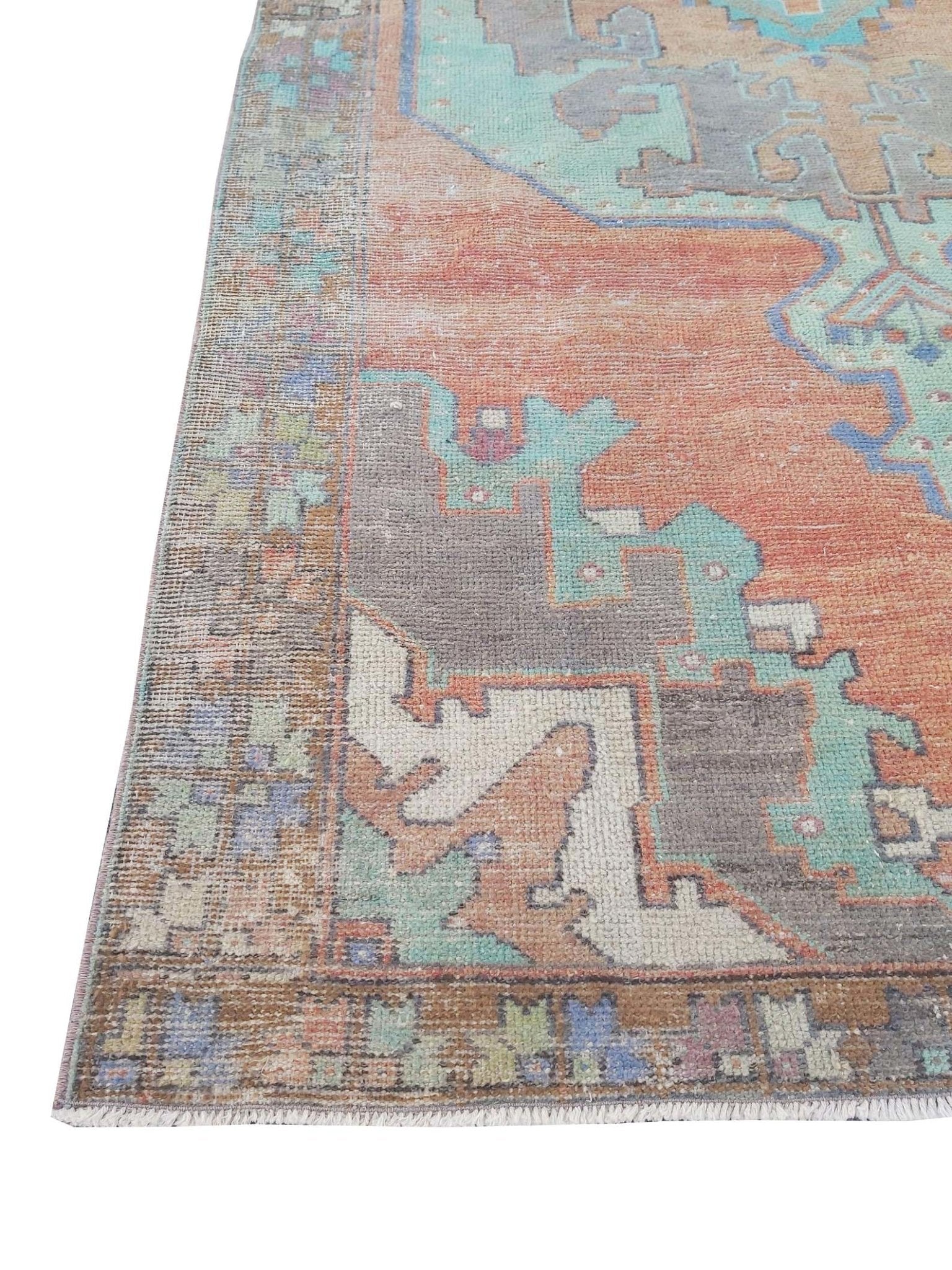 A vintage handmade Turkish rug featuring geometric patterns in orange, teal, and grey.