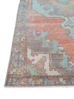 A vintage handmade Turkish rug featuring geometric patterns in orange, teal, and grey.