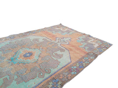 A vintage handmade Turkish rug featuring geometric patterns in shades of orange and teal.
