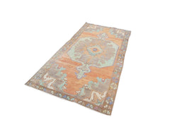 A vintage handmade Turkish rug featuring a geometric orange and teal pattern.