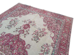 A vintage handmade Turkish wool rug featuring a cream field with pink floral and medallion motifs.
