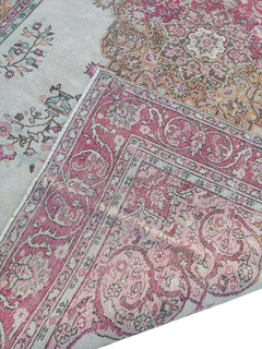 A vintage handmade Turkish wool rug featuring a pink and cream floral pattern.