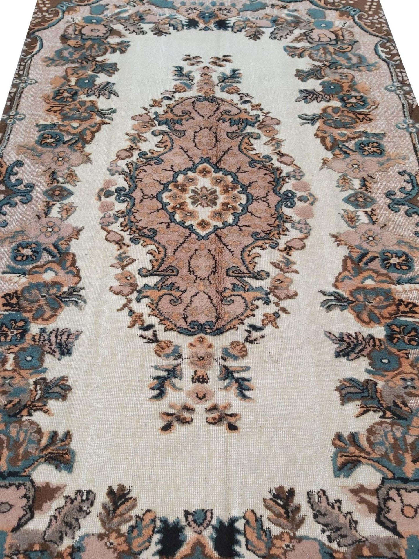 A vintage handmade Turkish Isparta rug featuring a central floral medallion in soft pink and blue tones.