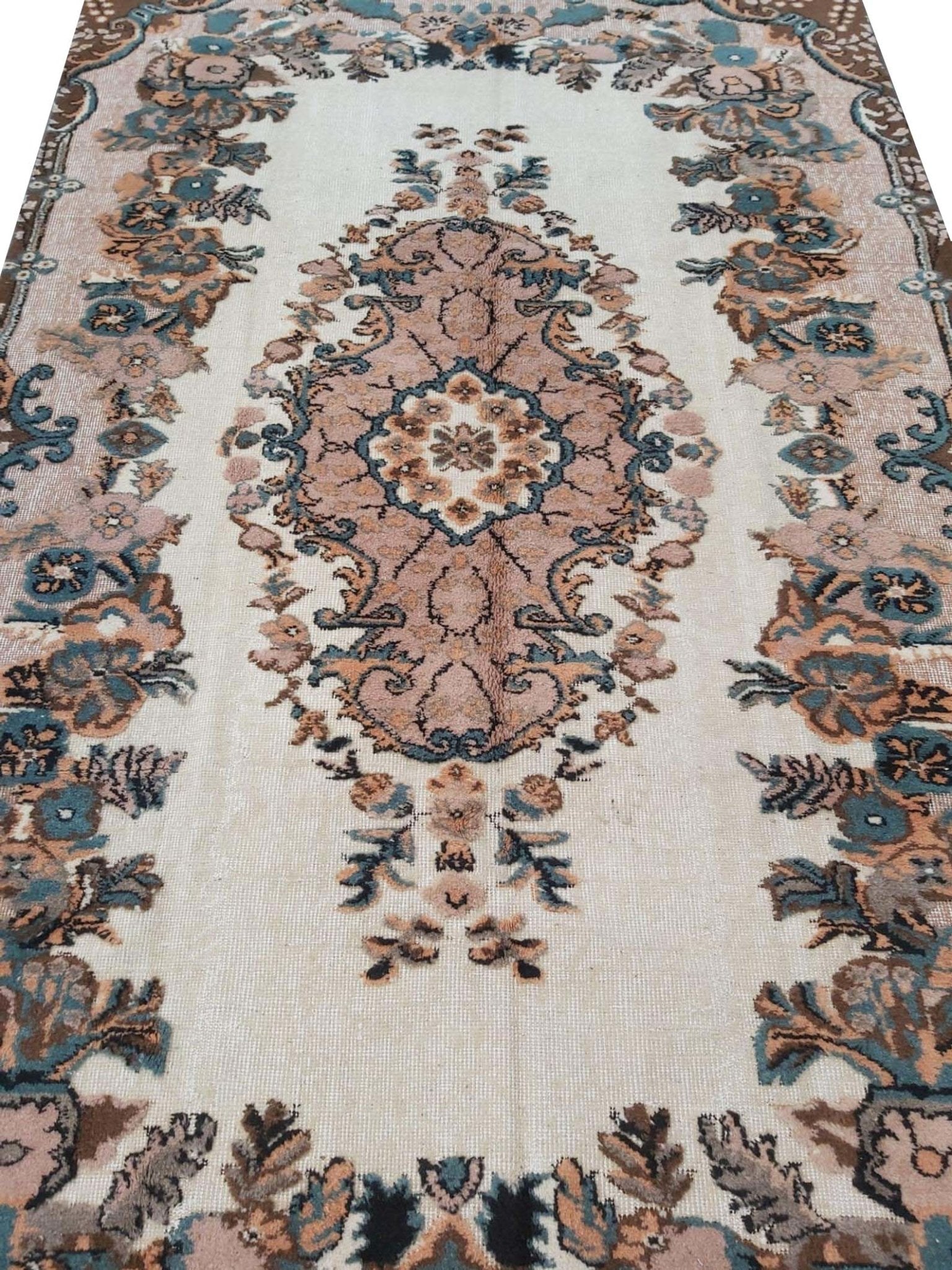 A vintage handmade Turkish Isparta rug featuring a central floral medallion in soft pink and blue tones.