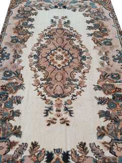 A vintage handmade Turkish Isparta rug featuring a central floral medallion in soft pink and blue tones.