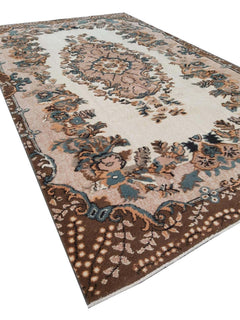 A vintage handmade Turkish Isparta rug featuring a floral medallion on a cream field with a brown border.