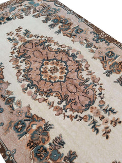 A vintage handmade Turkish Isparta rug featuring a floral medallion on a cream background.