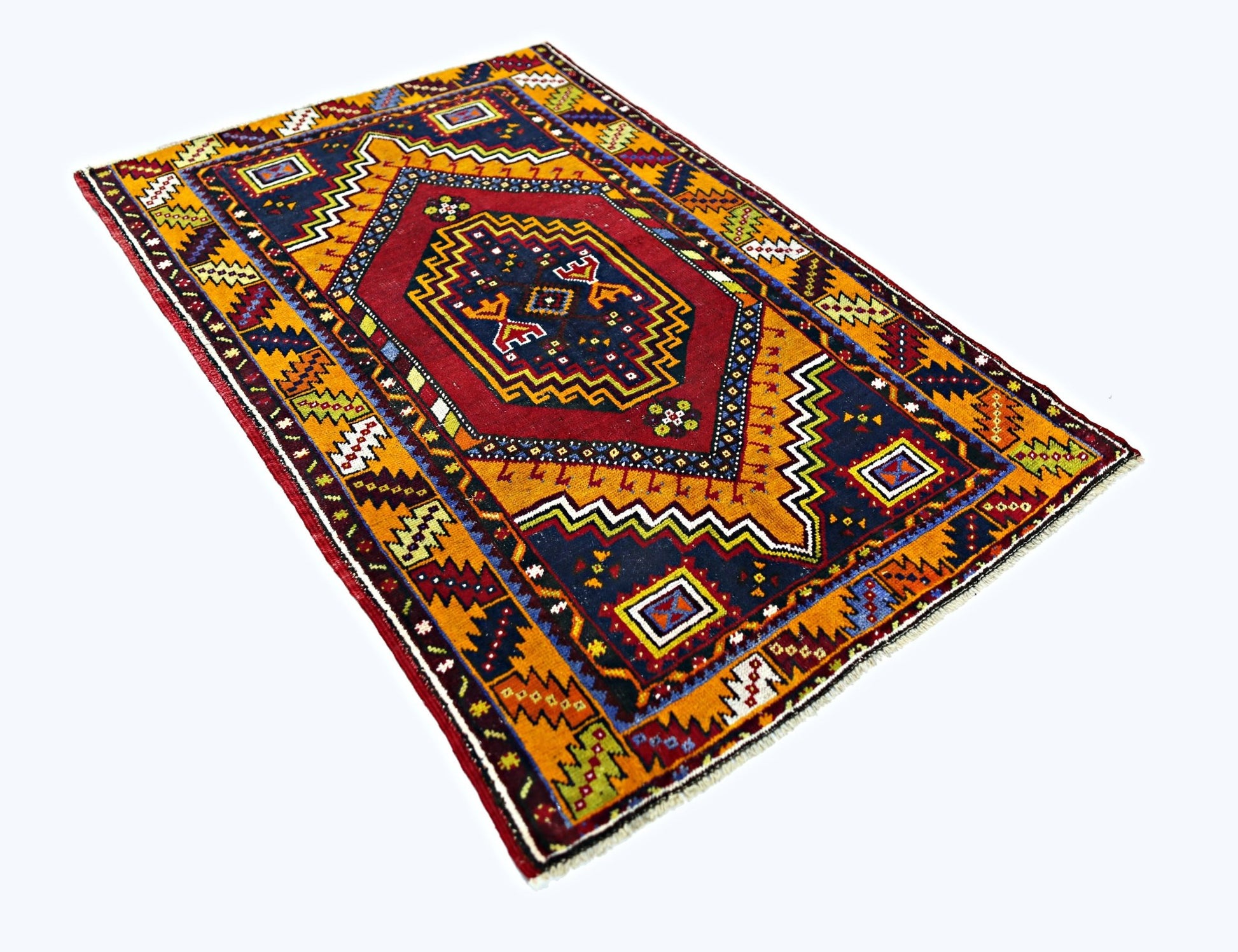 A vintage Turkish Taspinar rug featuring a geometric red medallion on a dark blue and orange field.
