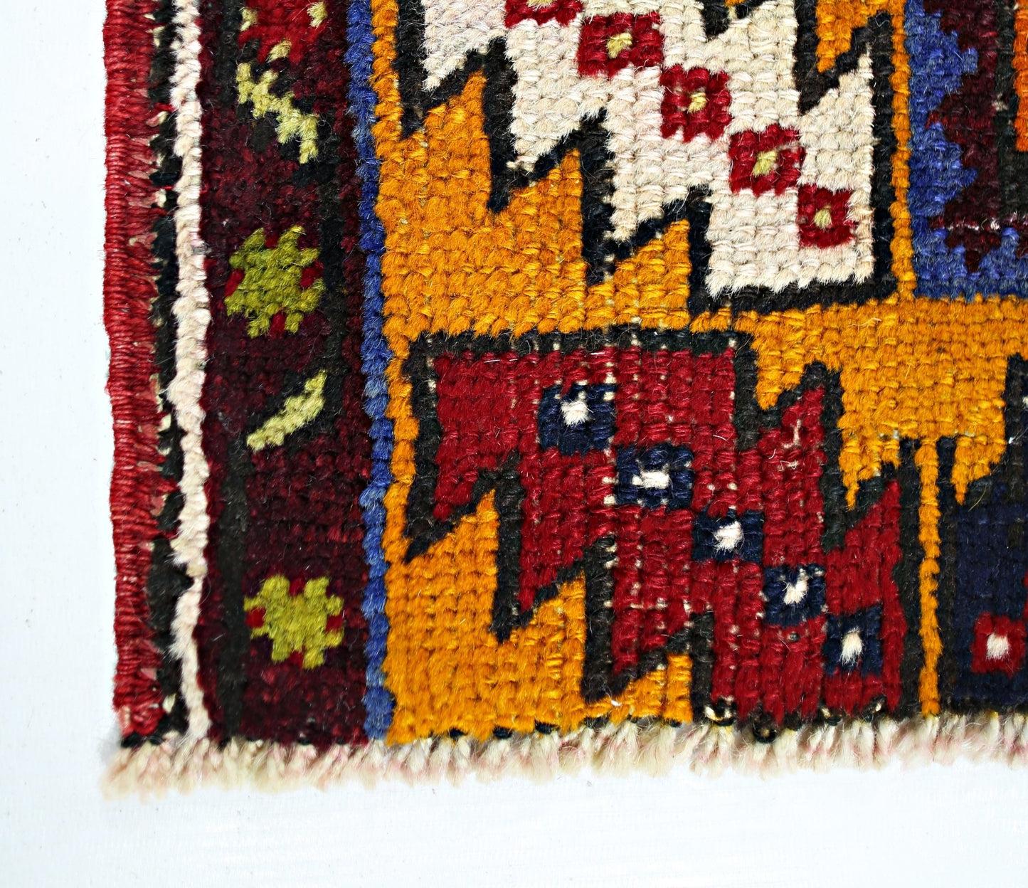 A close-up of a vintage Turkish Taspinar rug featuring geometric patterns in red, yellow, and blue.