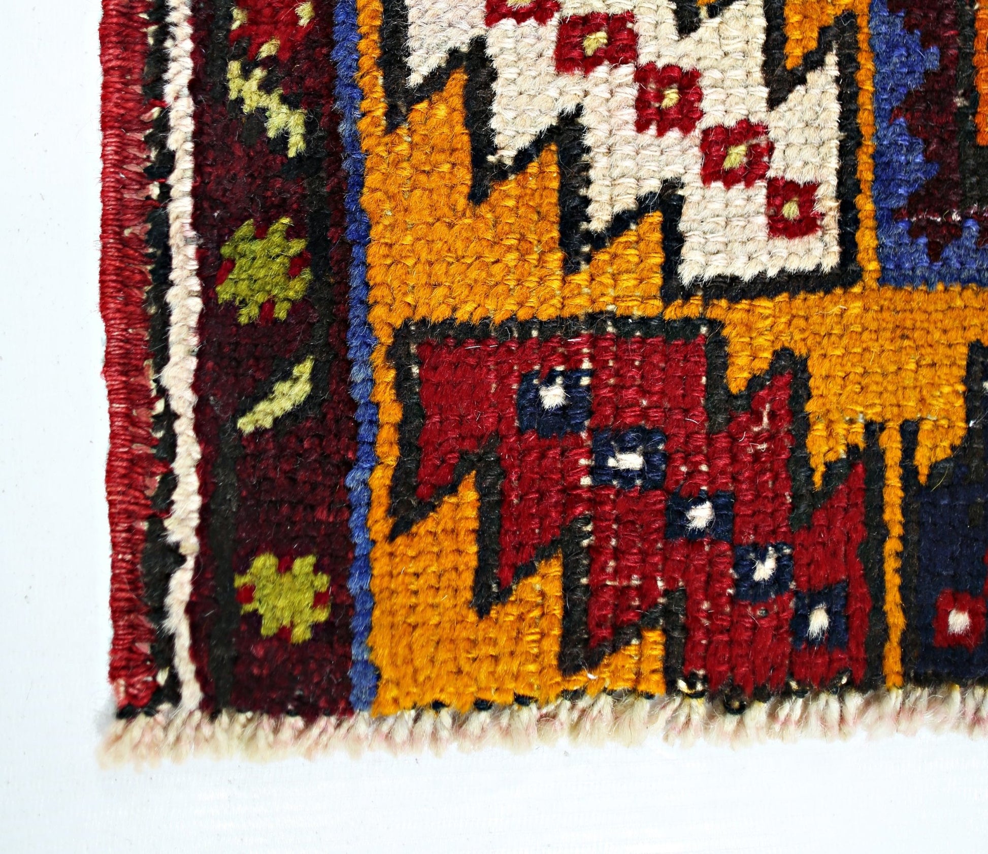 A close-up of a vintage Turkish Taspinar rug featuring geometric patterns in red, yellow, and blue.