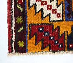 A close-up of a vintage Turkish Taspinar rug featuring geometric patterns in red, yellow, and blue.