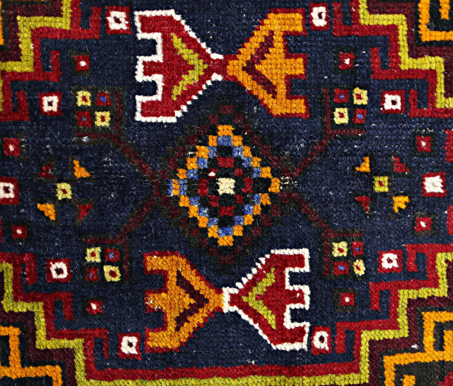 A vintage Turkish Taspinar rug featuring a geometric pattern in red, yellow, and blue on navy wool.