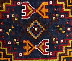 A vintage Turkish Taspinar rug featuring a geometric pattern in red, yellow, and blue on navy wool.