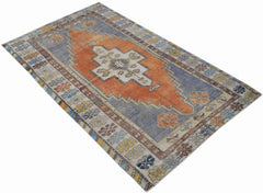 A vintage handwoven Turkish Taspinar rug featuring a central orange medallion on a blue field.