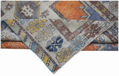 A vintage handwoven Turkish Taspinar rug featuring geometric patterns in orange, blue, and yellow.