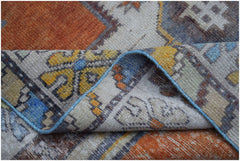A vintage handwoven Turkish Taspinar rug featuring a geometric pattern in orange, blue, and yellow.