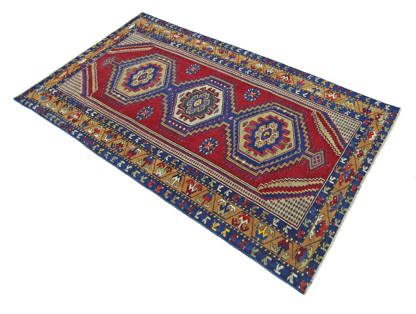 A handmade vintage Persian rug featuring three central geometric medallions on a red field.