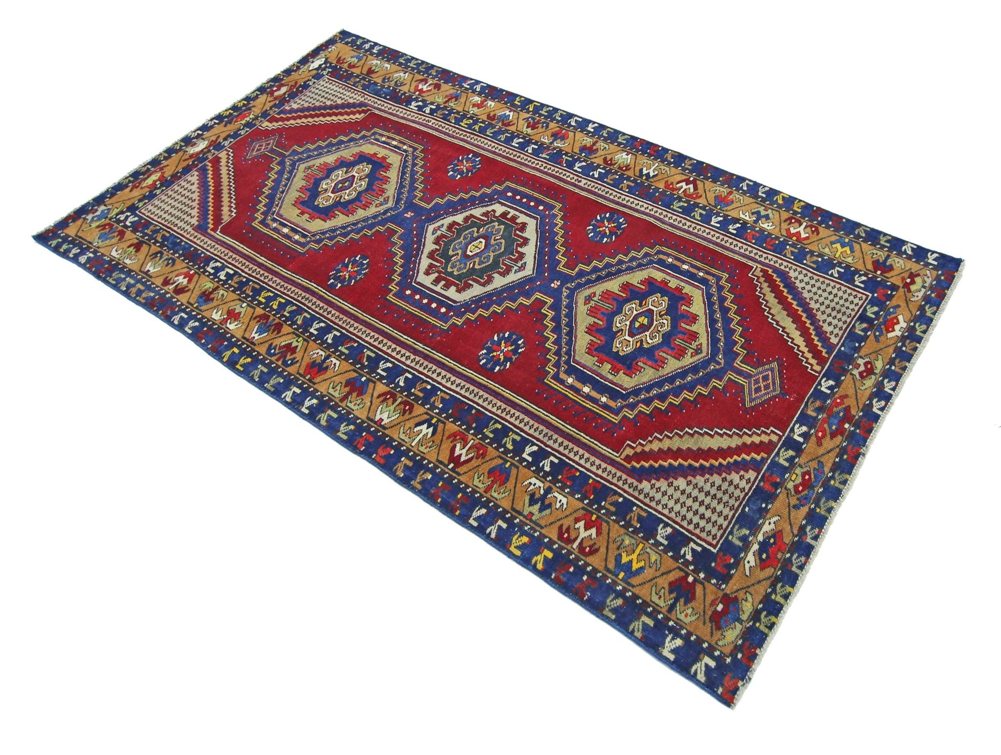 A handmade vintage Persian rug featuring three central geometric medallions on a red field.