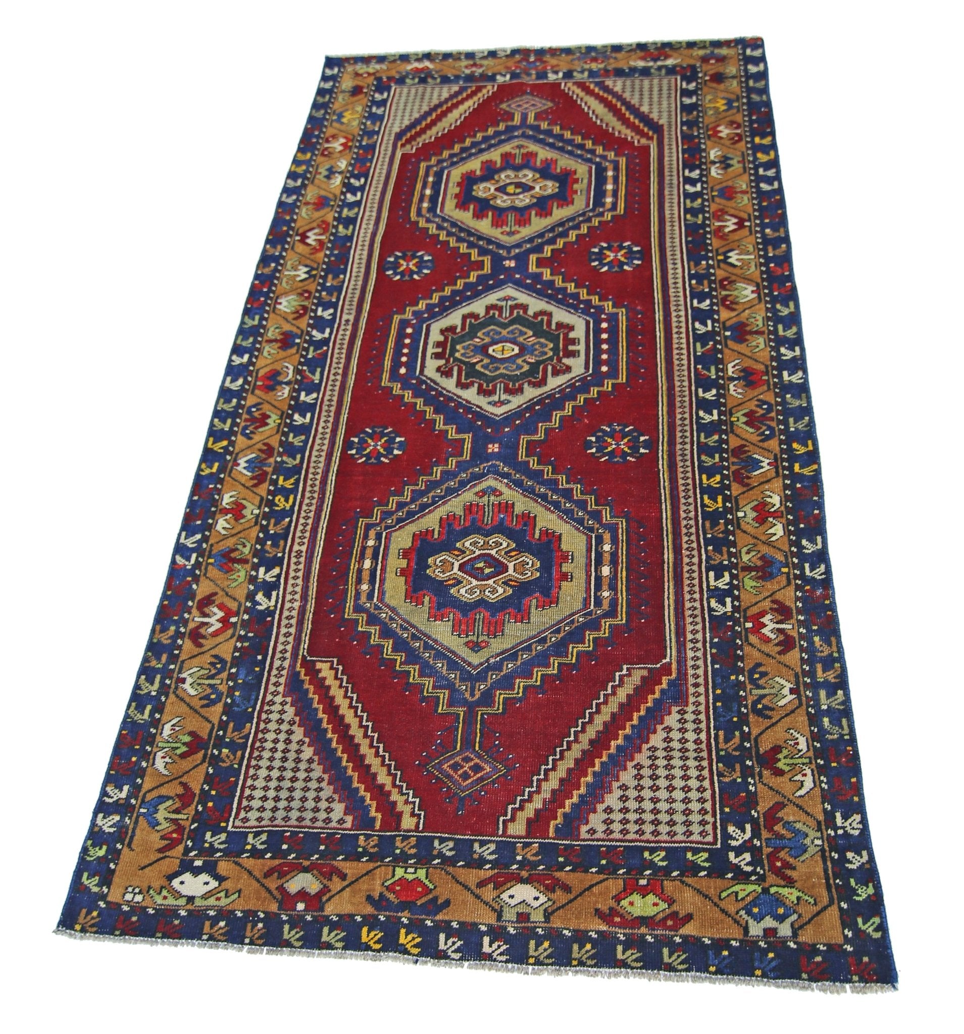A handmade vintage Persian runner rug featuring three geometric medallions on a red field.