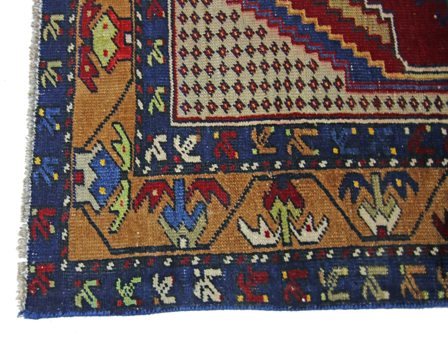 A vintage Persian rug featuring geometric patterns in blue, red, and tan wool.