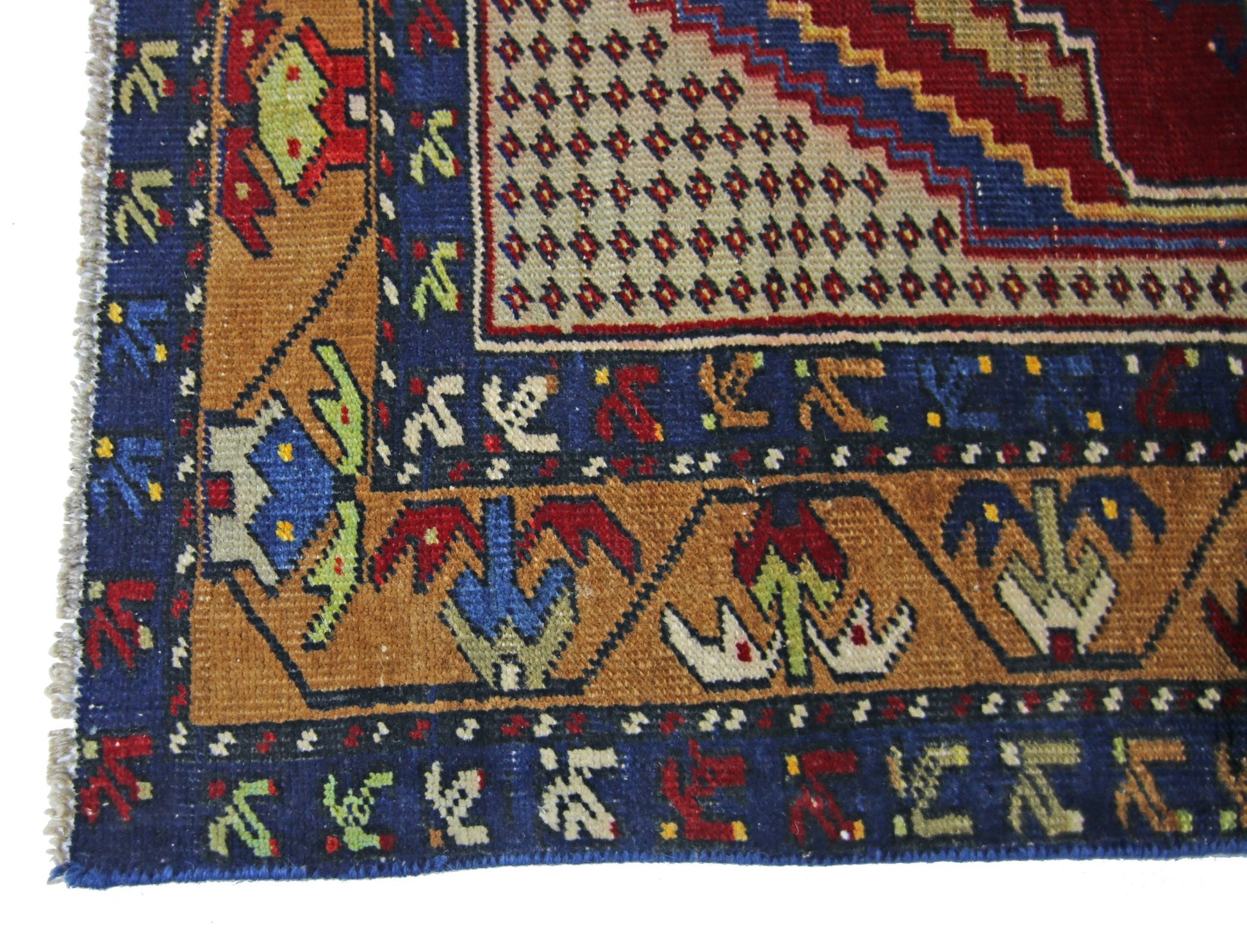 A vintage Persian rug featuring geometric patterns in blue, red, and tan wool.