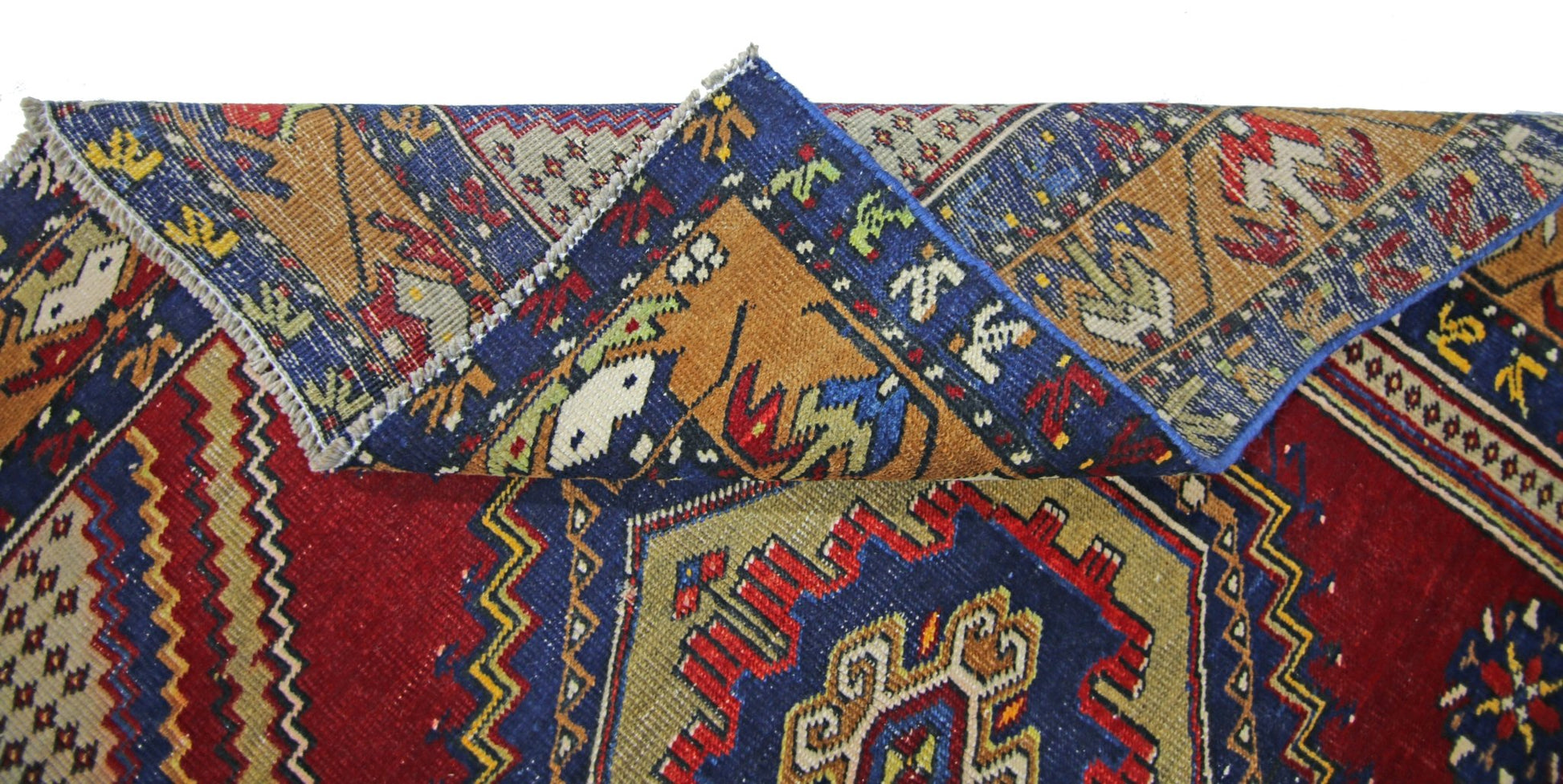 A vintage handmade Persian rug featuring a geometric pattern in red, blue, and gold tones.