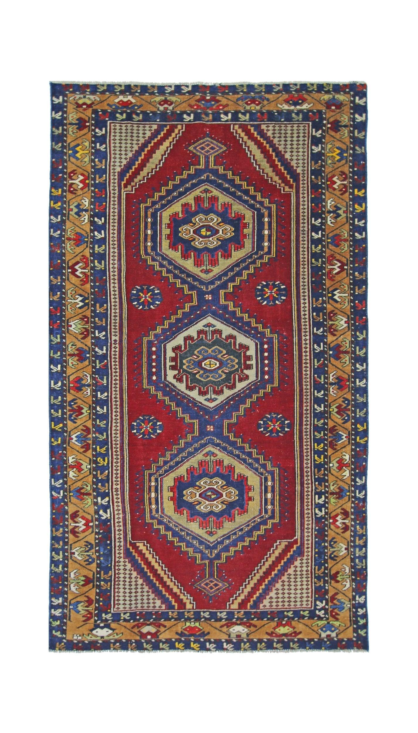 A handmade vintage Persian rug featuring three central geometric medallions on a red field.