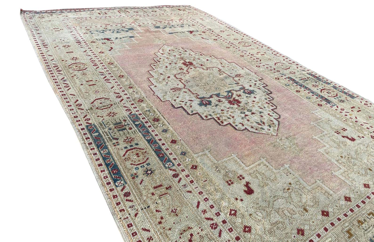 A vintage Turkish Taspinar rug featuring a soft pink field with geometric motifs and a central medallion.