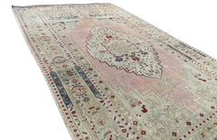 A vintage Turkish Taspinar rug featuring a soft pink field with geometric motifs and a central medallion.
