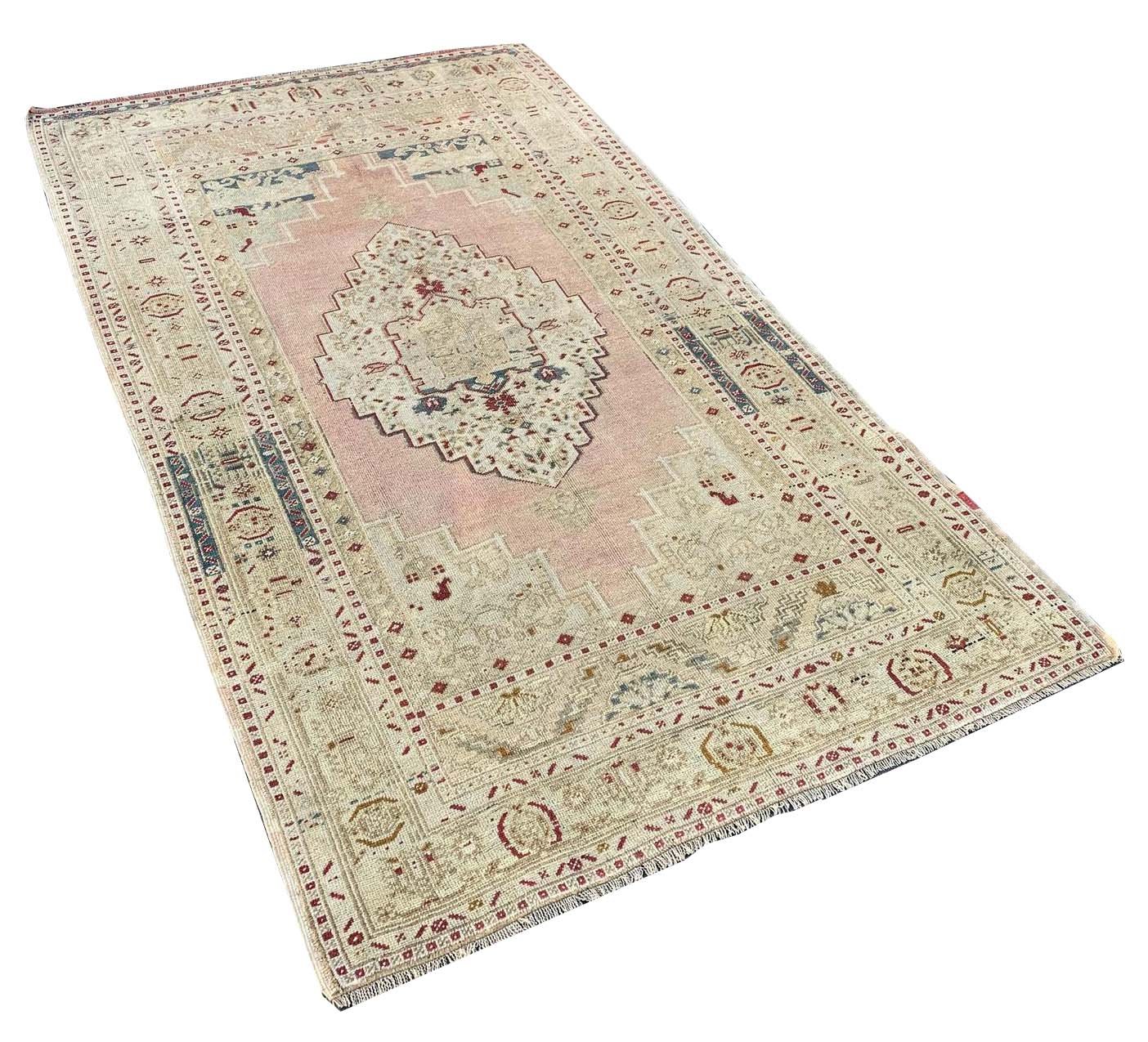 A vintage handmade Turkish Taspinar rug featuring a geometric medallion on a soft pink field.
