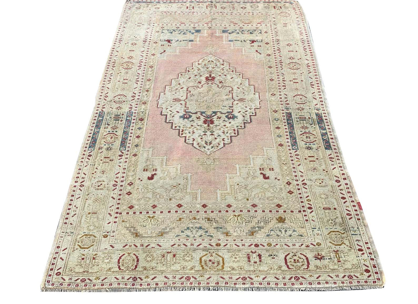 A vintage handmade Turkish Taspinar rug featuring a geometric medallion on a soft pink field.