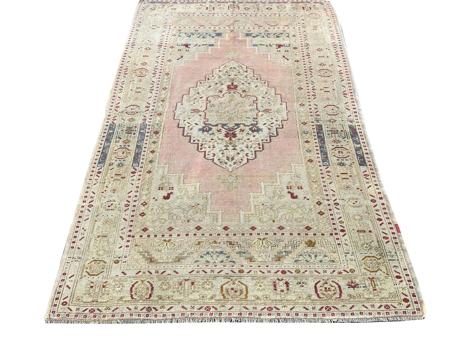 A vintage handmade Turkish Taspinar rug featuring a geometric medallion on a soft pink field.