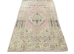 A vintage handmade Turkish Taspinar rug featuring a geometric medallion on a soft pink field.