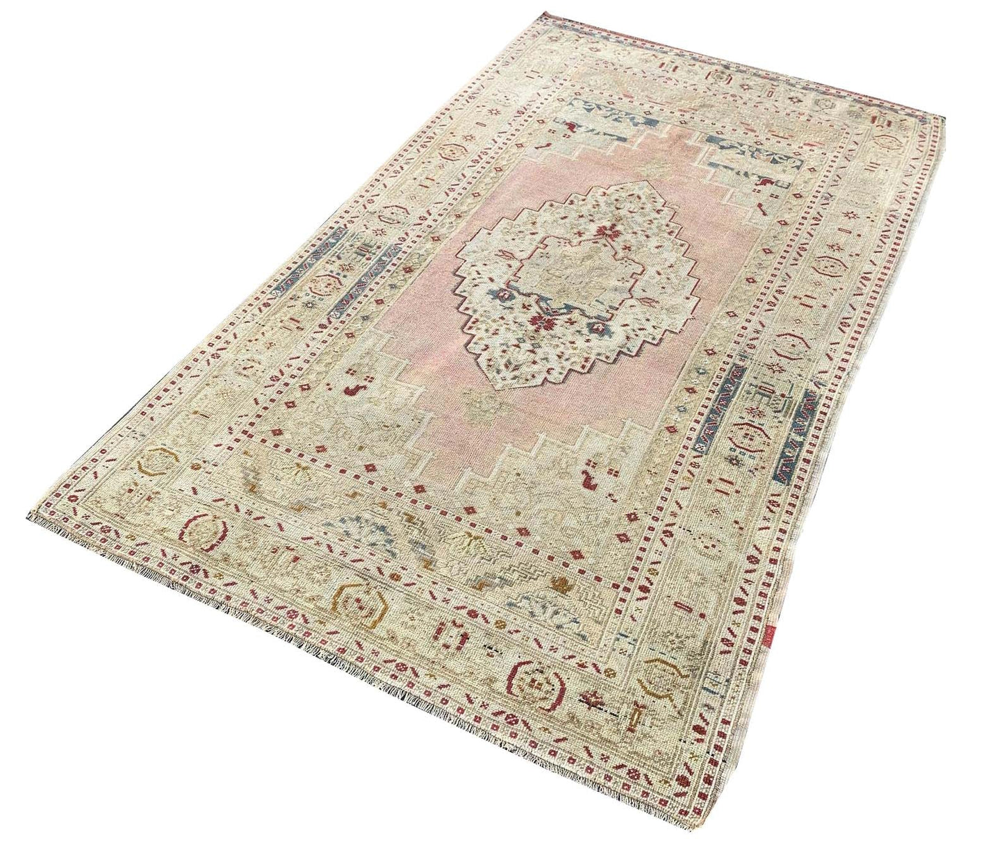A vintage handmade Turkish Taspinar rug featuring soft pink and beige geometric patterns.