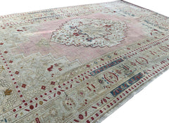 A vintage Turkish Taspinar rug featuring a soft pink field with geometric motifs and a beige border.