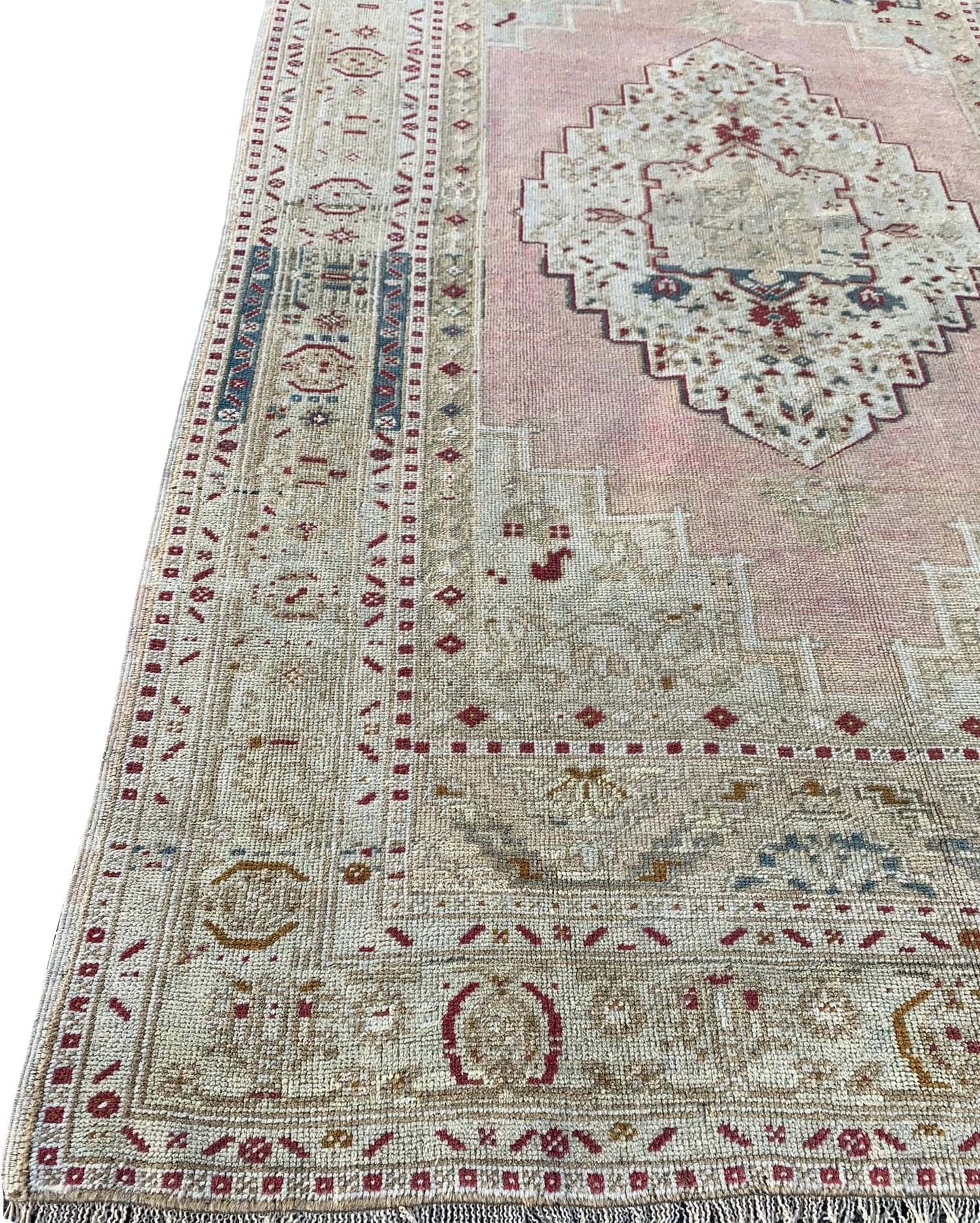 A vintage handmade Turkish Taspinar rug featuring a geometric medallion on a soft pink field.