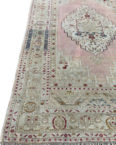 A vintage handmade Turkish Taspinar rug featuring a geometric medallion on a soft pink field.