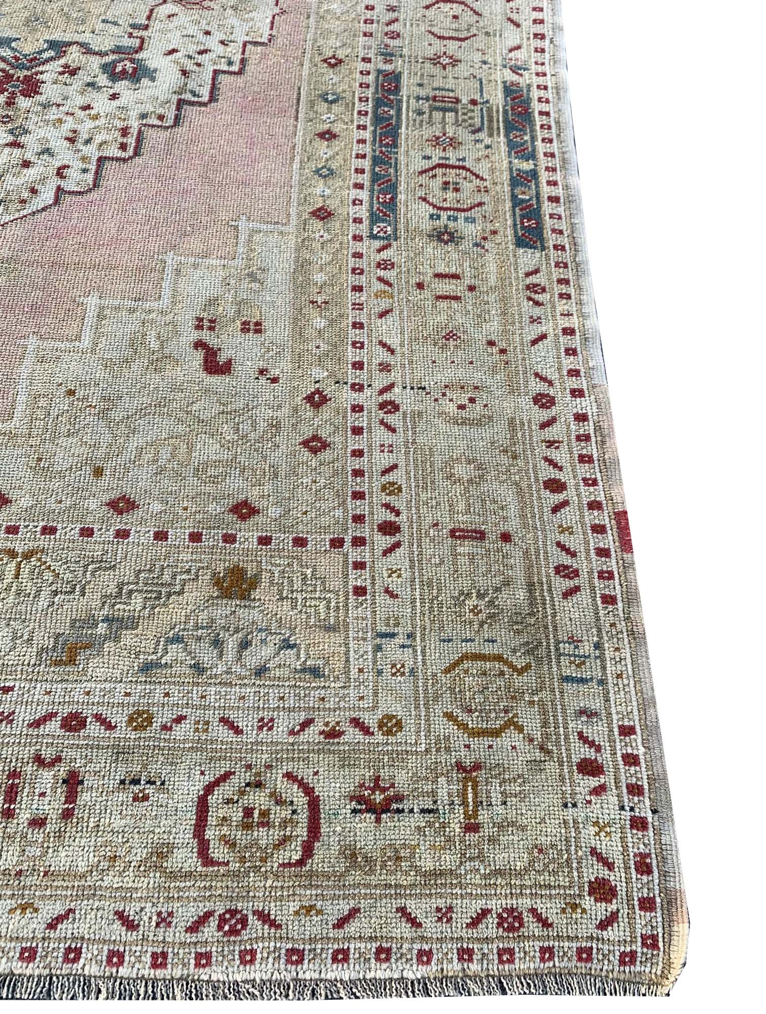 A vintage handwoven Turkish Taspinar rug featuring soft colors and geometric Persian motifs.