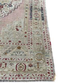 A vintage handwoven Turkish Taspinar rug featuring soft colors and geometric Persian motifs.
