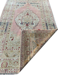 A vintage handmade Turkish Taspinar rug featuring soft pink tones and geometric motifs.