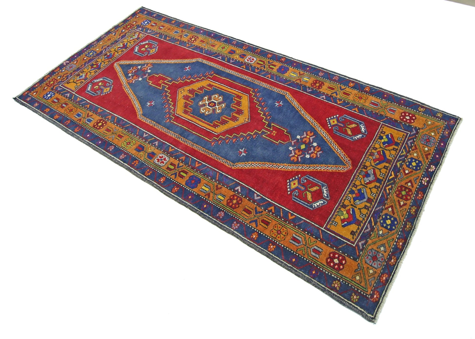 A vintage handmade Turkish Taspinar rug featuring a geometric blue medallion on a red field.