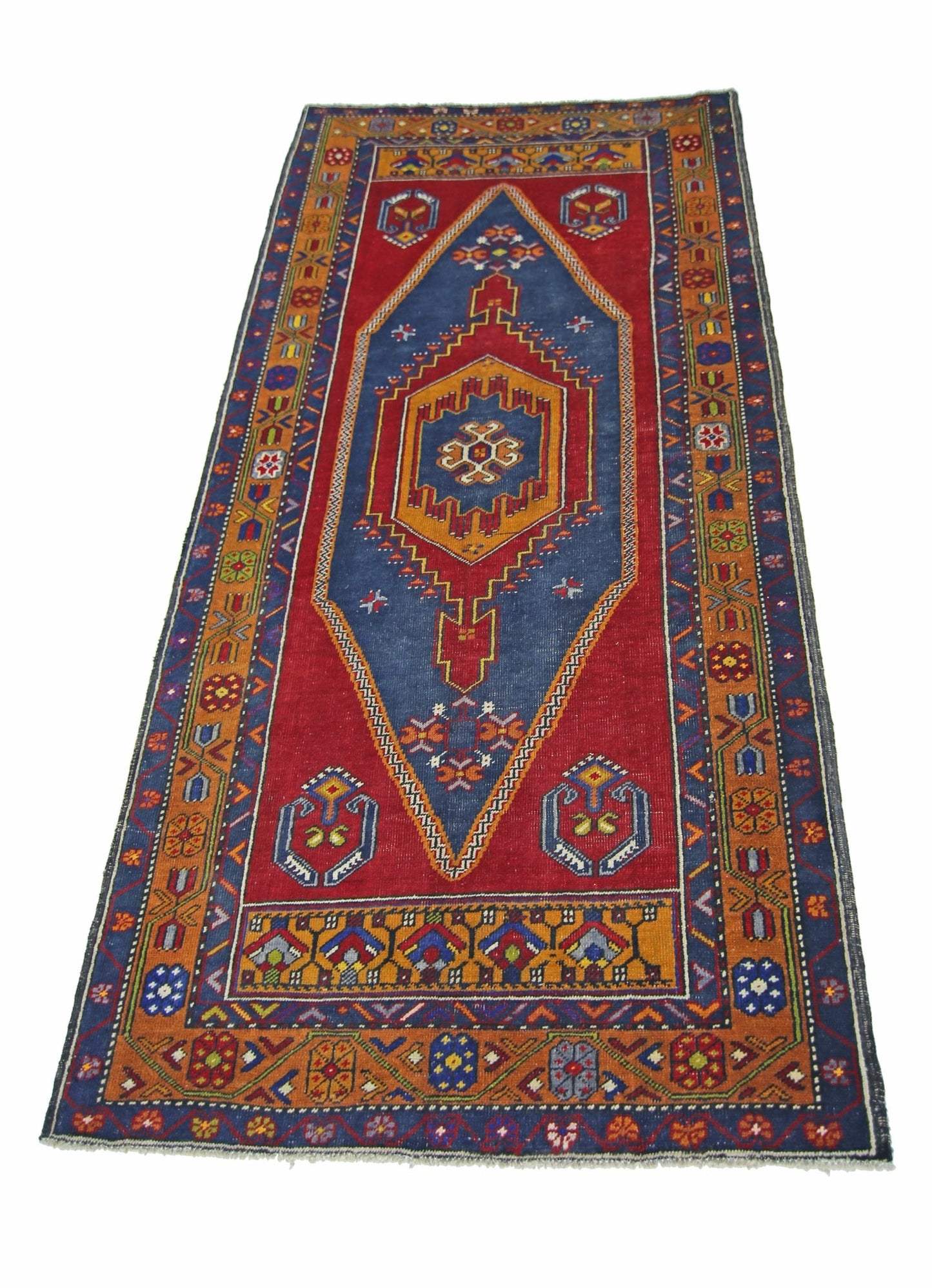 A vintage handmade Turkish Taspinar runner rug featuring a central diamond motif on a red field.